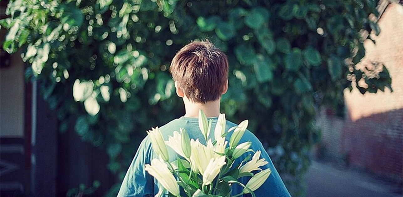 Person with flowers behind their back.