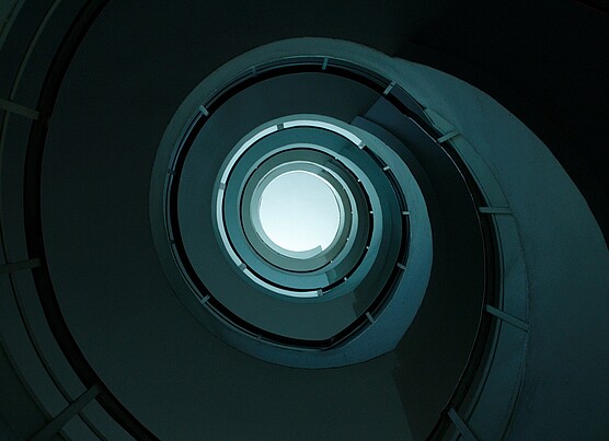 Spiraling multi-level parking garage with a central open void, offering a clear view of the sky through its circular opening.