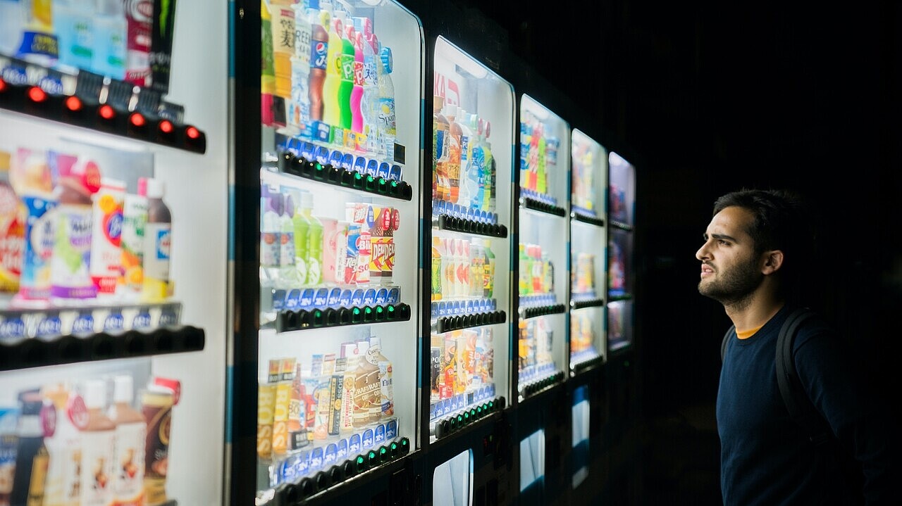 Person standing in front of a wall of vending machines, looking overwhelmed by the vast array of choices.