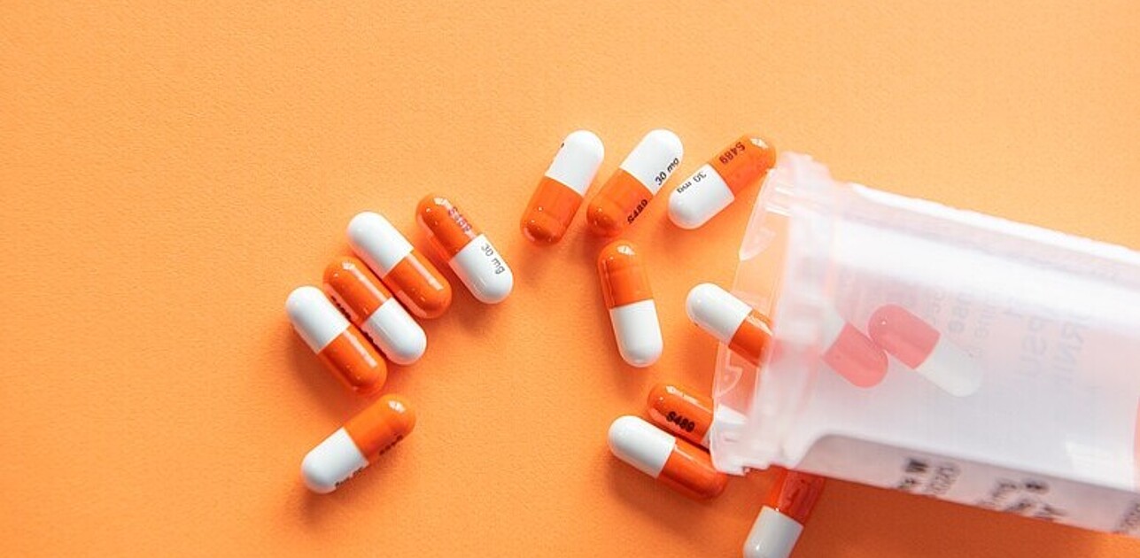 Medication displayed in front of an orange background.