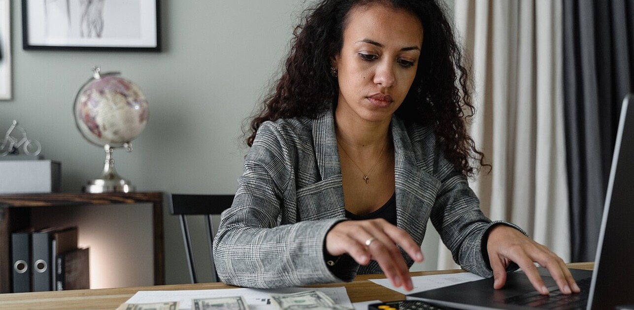 Accountant woman focused on making precise calculations using a calculator beside her laptop, ensuring financial accuracy.