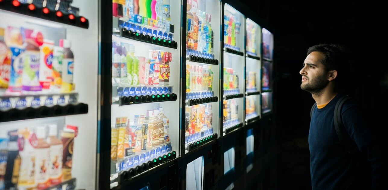 a man looking at different vending machines, deciding what product to chose