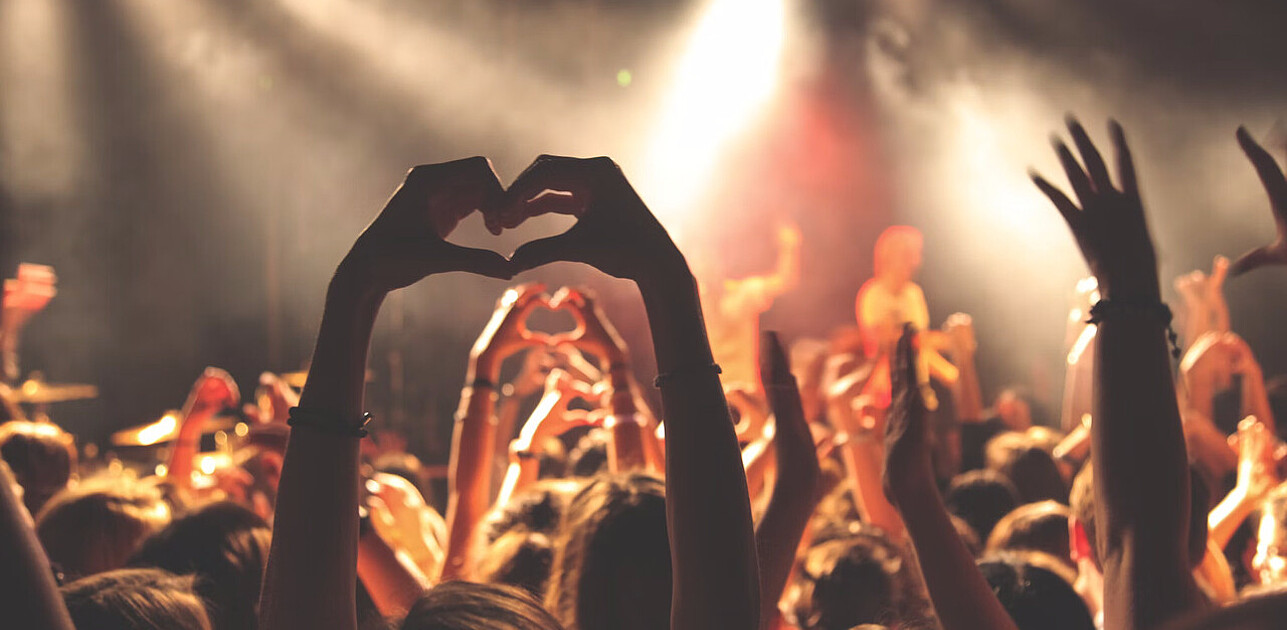 People holding up their hands in a heart formation for a concert