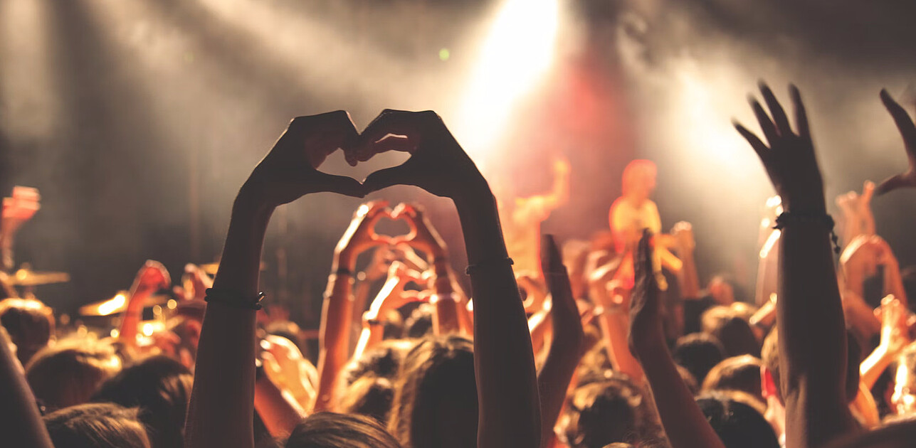 People holding up their hands in a heart formation for a concert