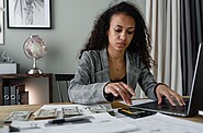 Accountant woman focused on making precise calculations using a calculator beside her laptop, ensuring financial accuracy.