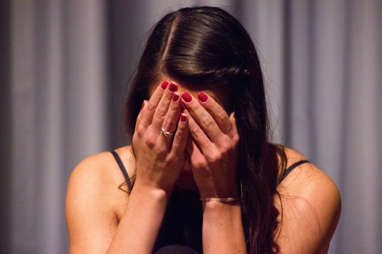 Woman covering her face with her hands, displaying a gesture of shame or distress.